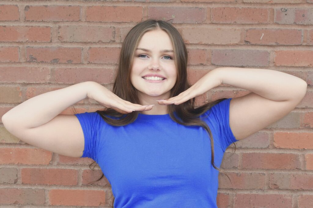 Patient framing her smile after orthodontic treatment at Pioneer Orthodontics